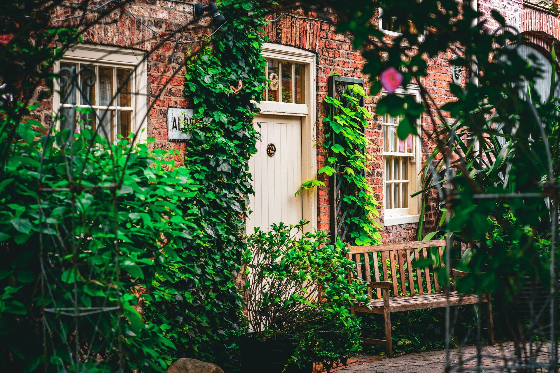 A brick house with a white door and a wooden bench in front of it.