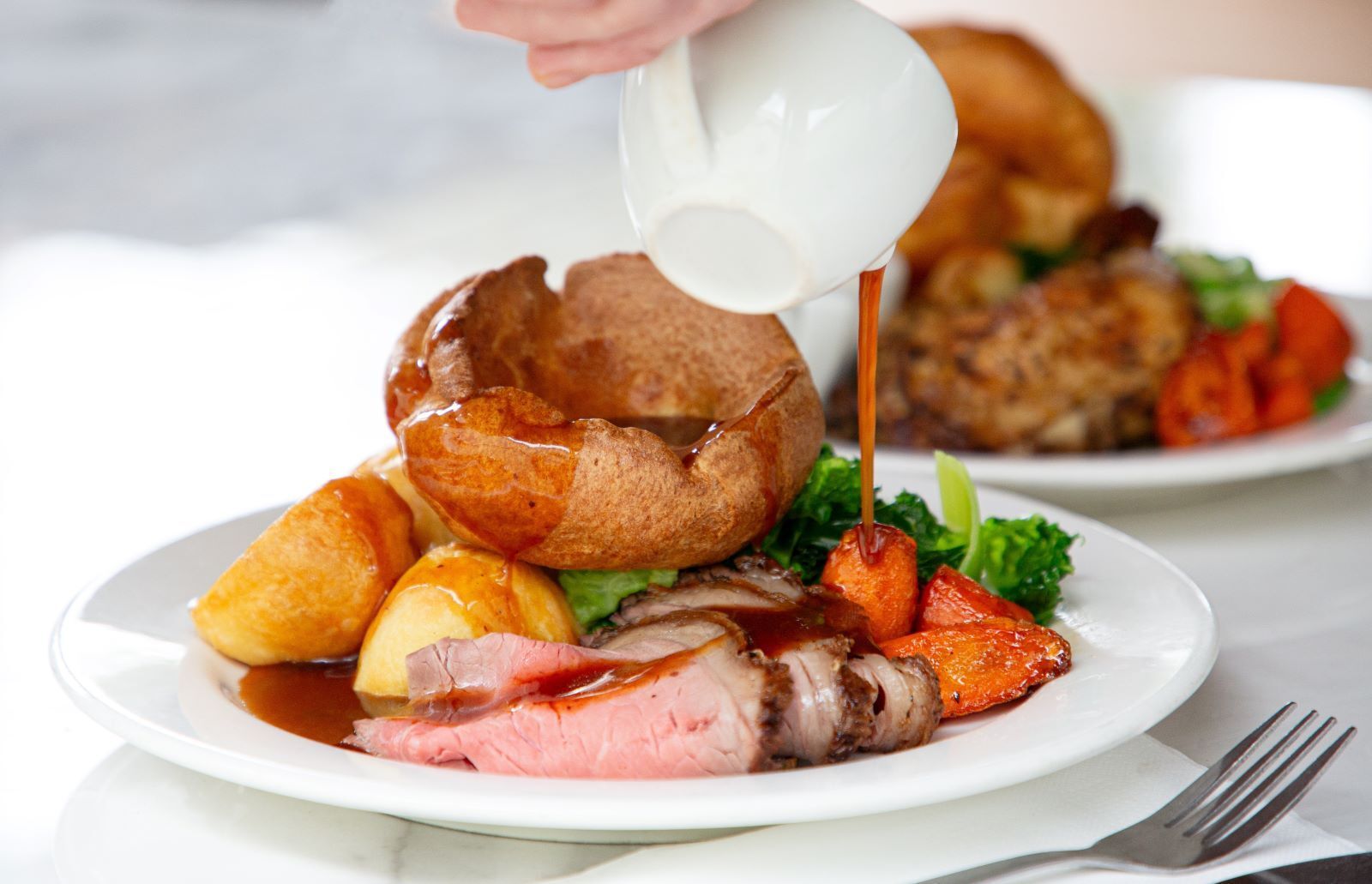 A white plate topped with meat potatoes and bread on a wooden table.