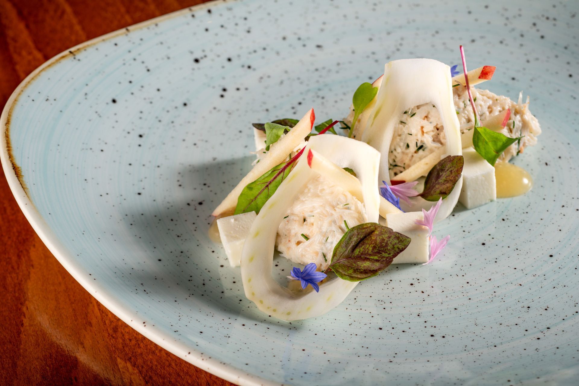 A blue plate with a sandwich on it on a wooden table.