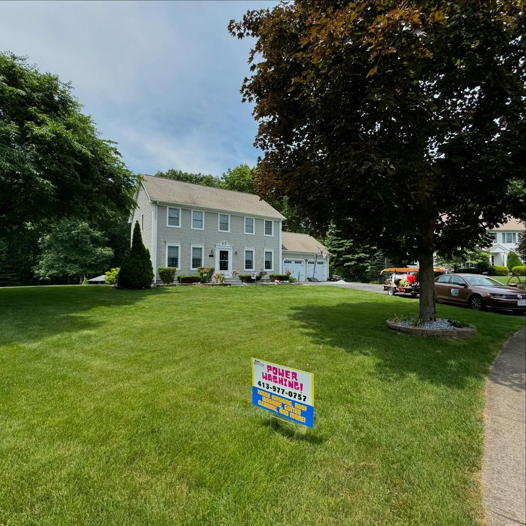 A lawn with a for sale sign in front of a house
