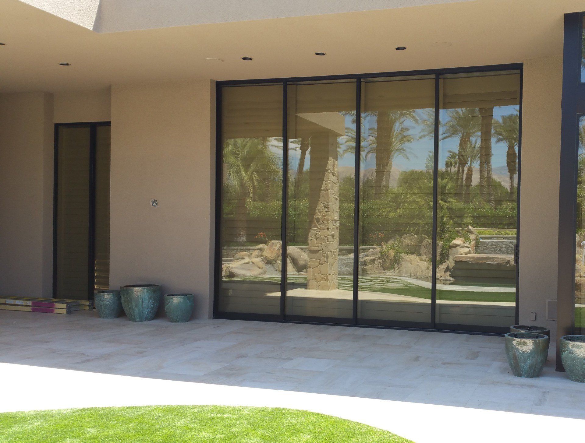 A house with a lot of windows and a reflection of palm trees