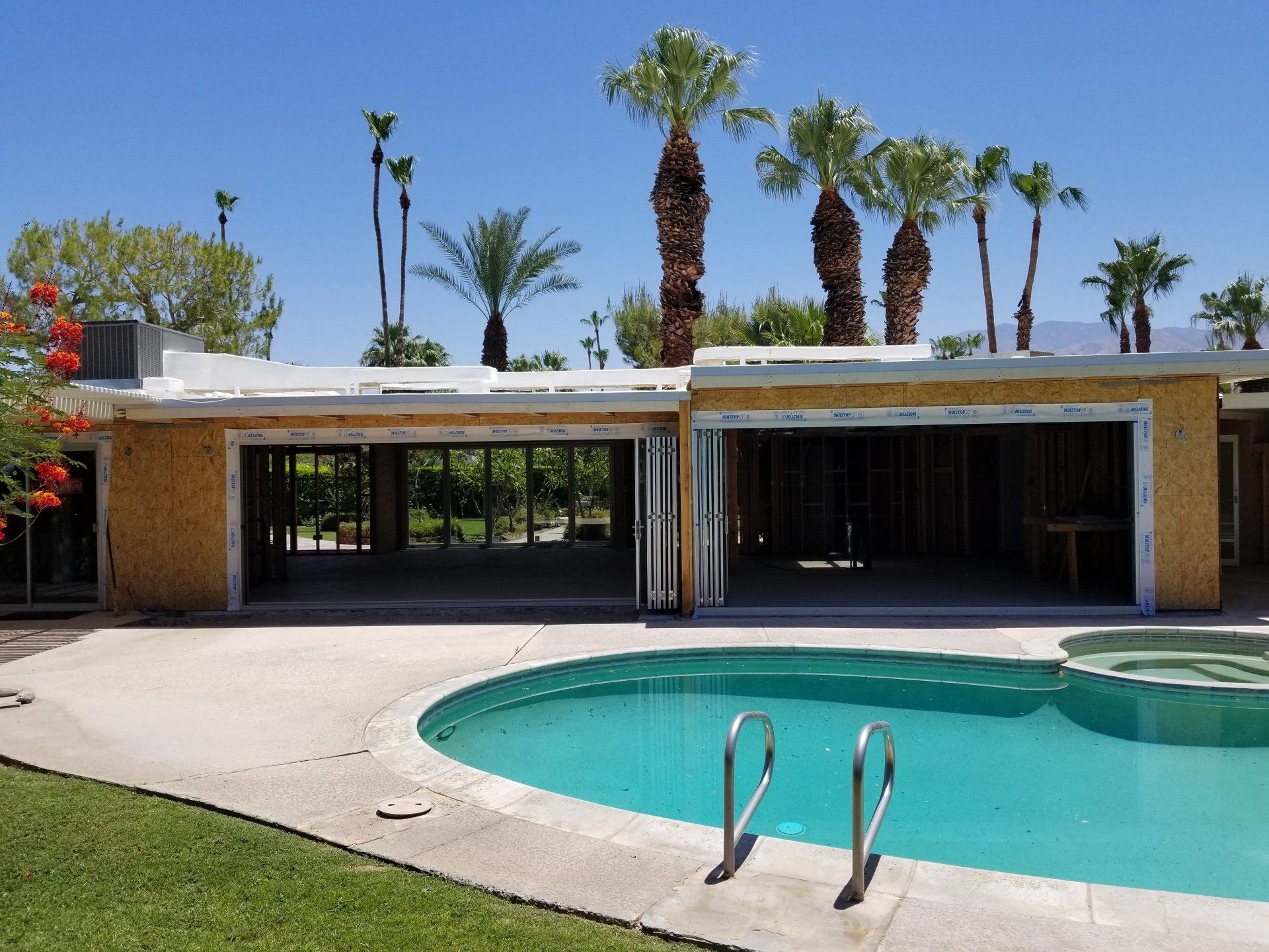 A swimming pool in front of a house with palm trees in the background