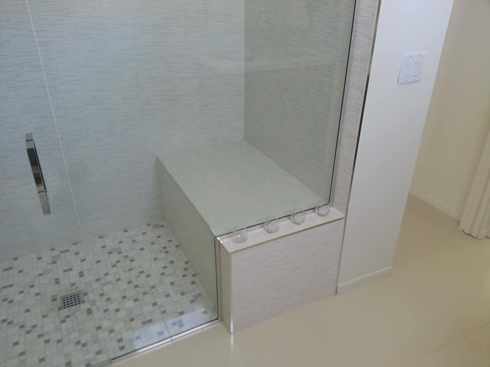 A bathroom with a walk in shower with a bench
