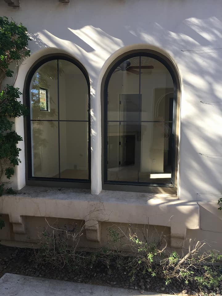 There are two arched windows on the side of a building.