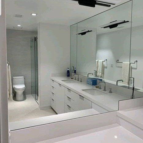 A bathroom with two sinks , a toilet , and a large mirror.