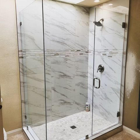 A bathroom with a walk in shower with a glass door.