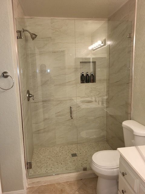 A bathroom with a toilet , sink , shower and glass door.