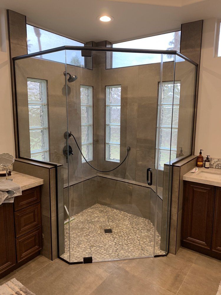 A bathroom with a walk in shower with a glass door.
