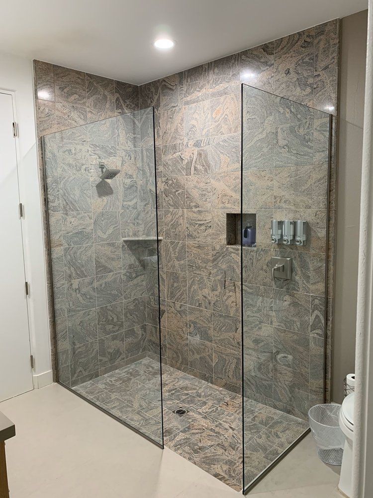 A bathroom with a walk in shower with a glass door.