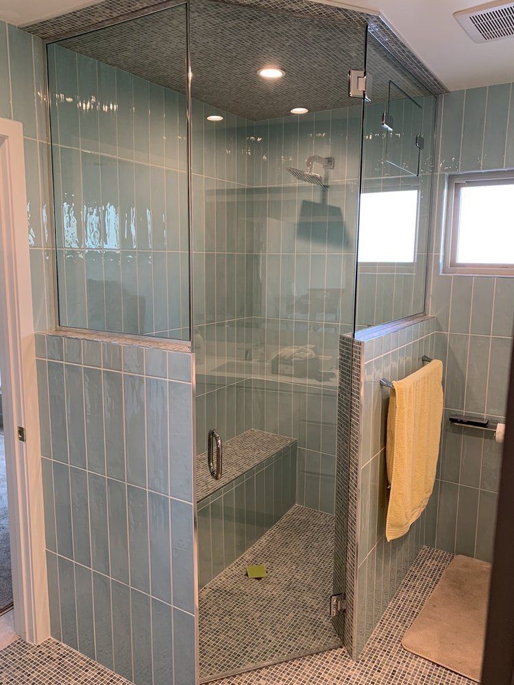 A bathroom with blue tiles and a walk in shower with a glass door.
