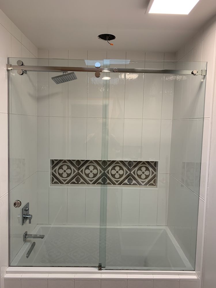 A bathroom with a bathtub and a shower with a sliding glass door.