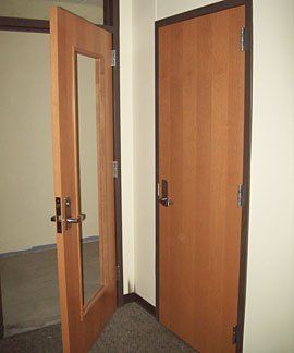 A hallway with two wooden doors and a mirror.