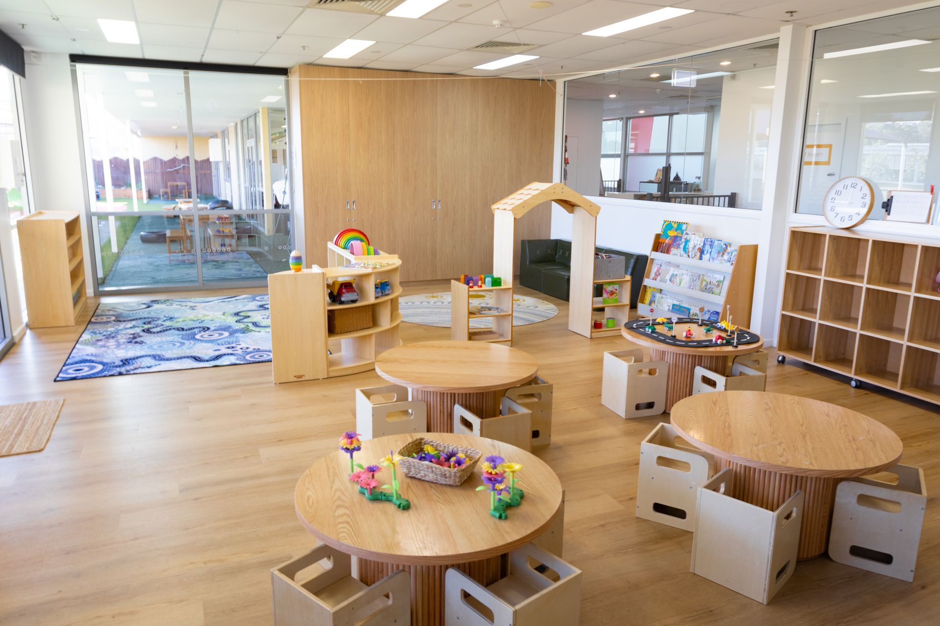 A classroom with wooden tables and chairs filled with toys.