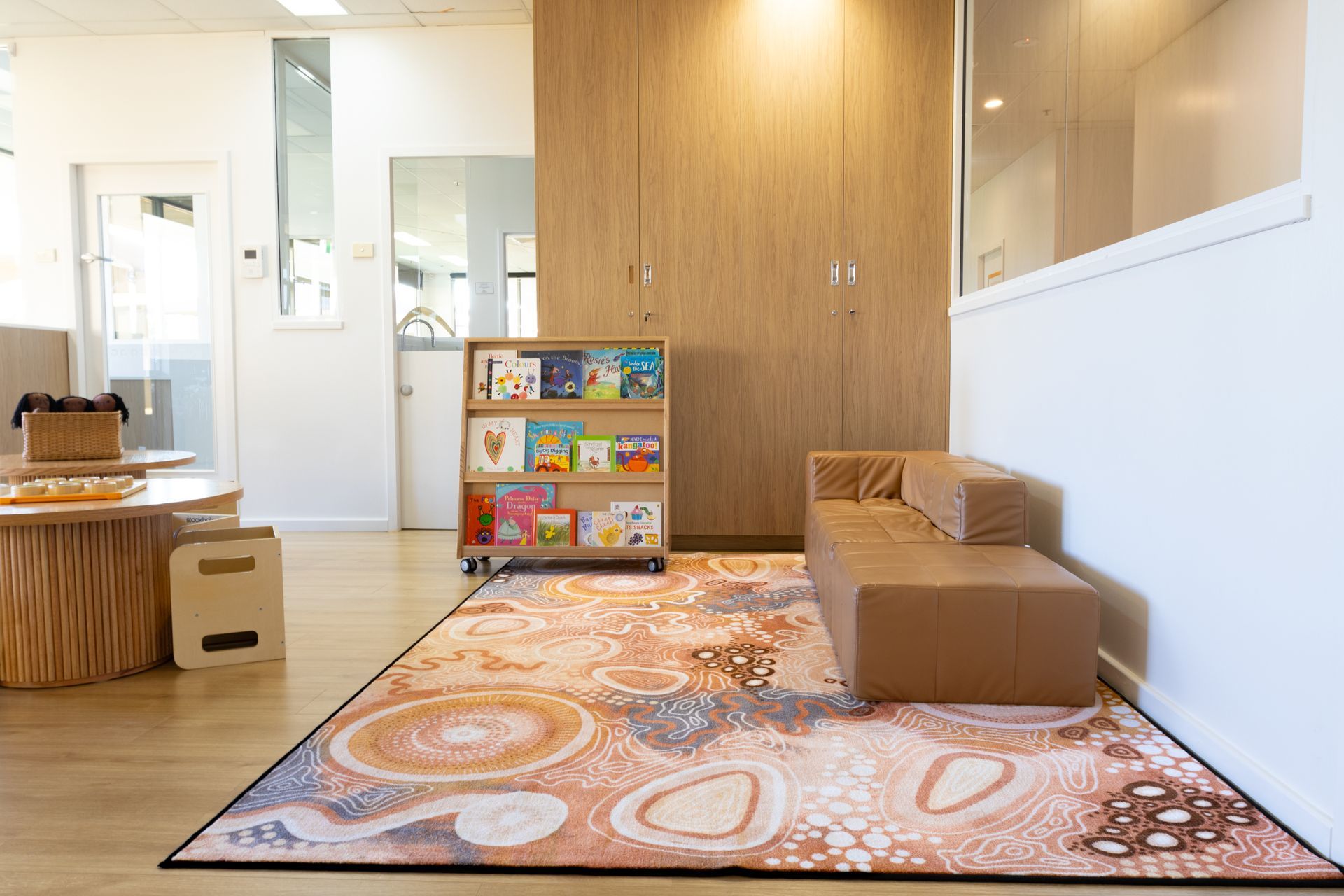 A room with a rug , a couch , a bookshelf and a table.