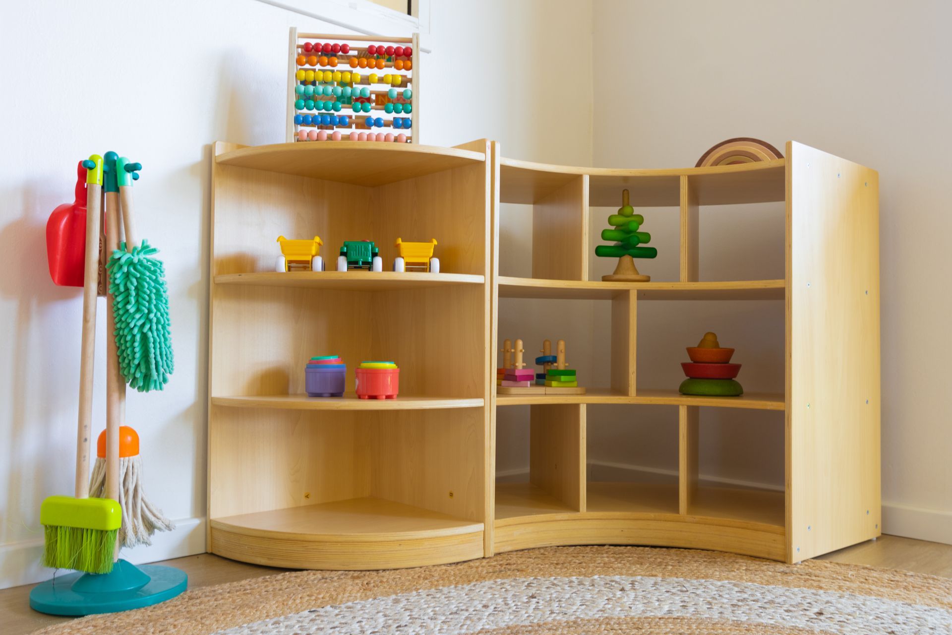 A room with wooden shelves filled with toys and a mop.