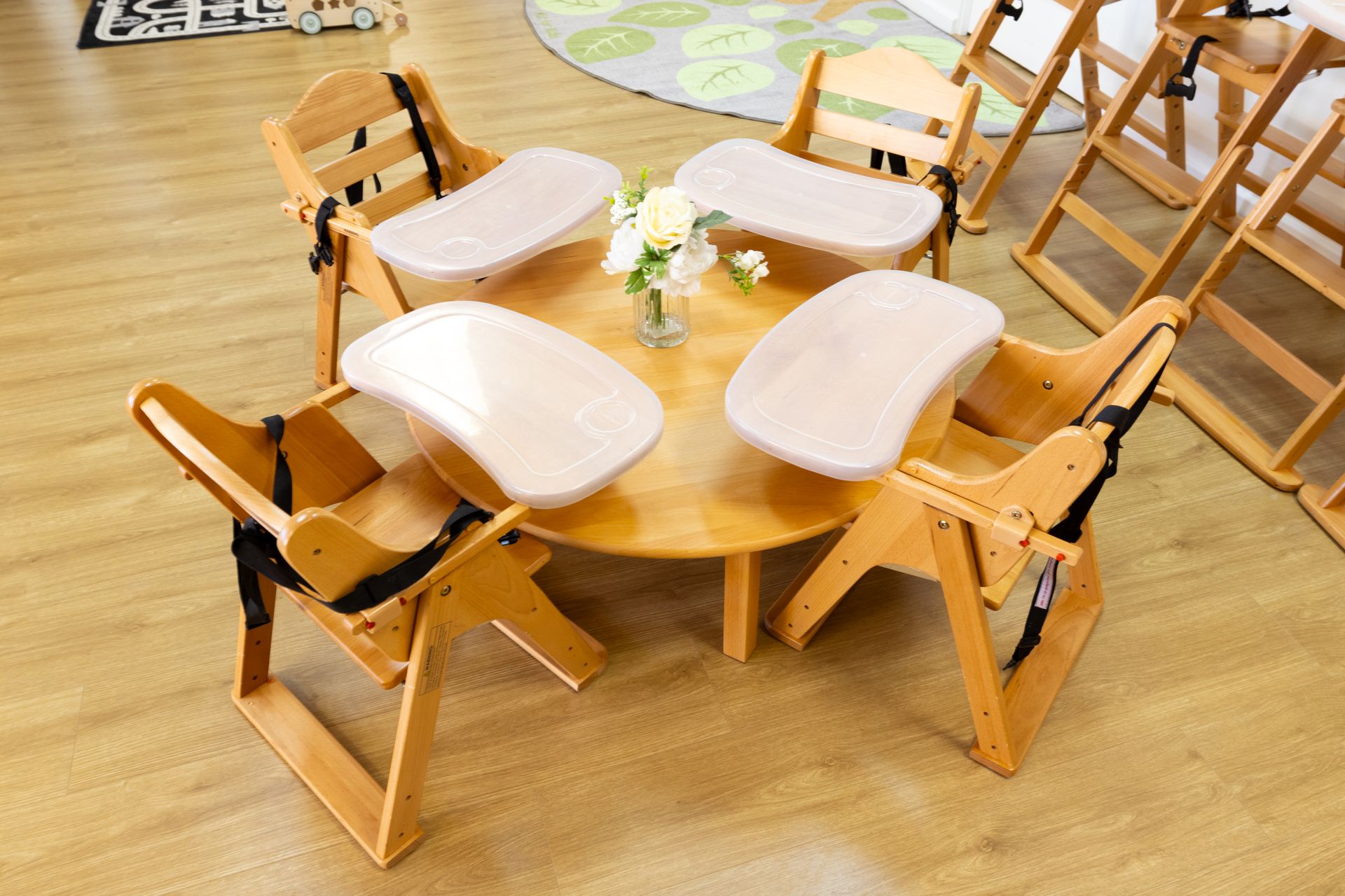 Four wooden high chairs are sitting around a wooden table.