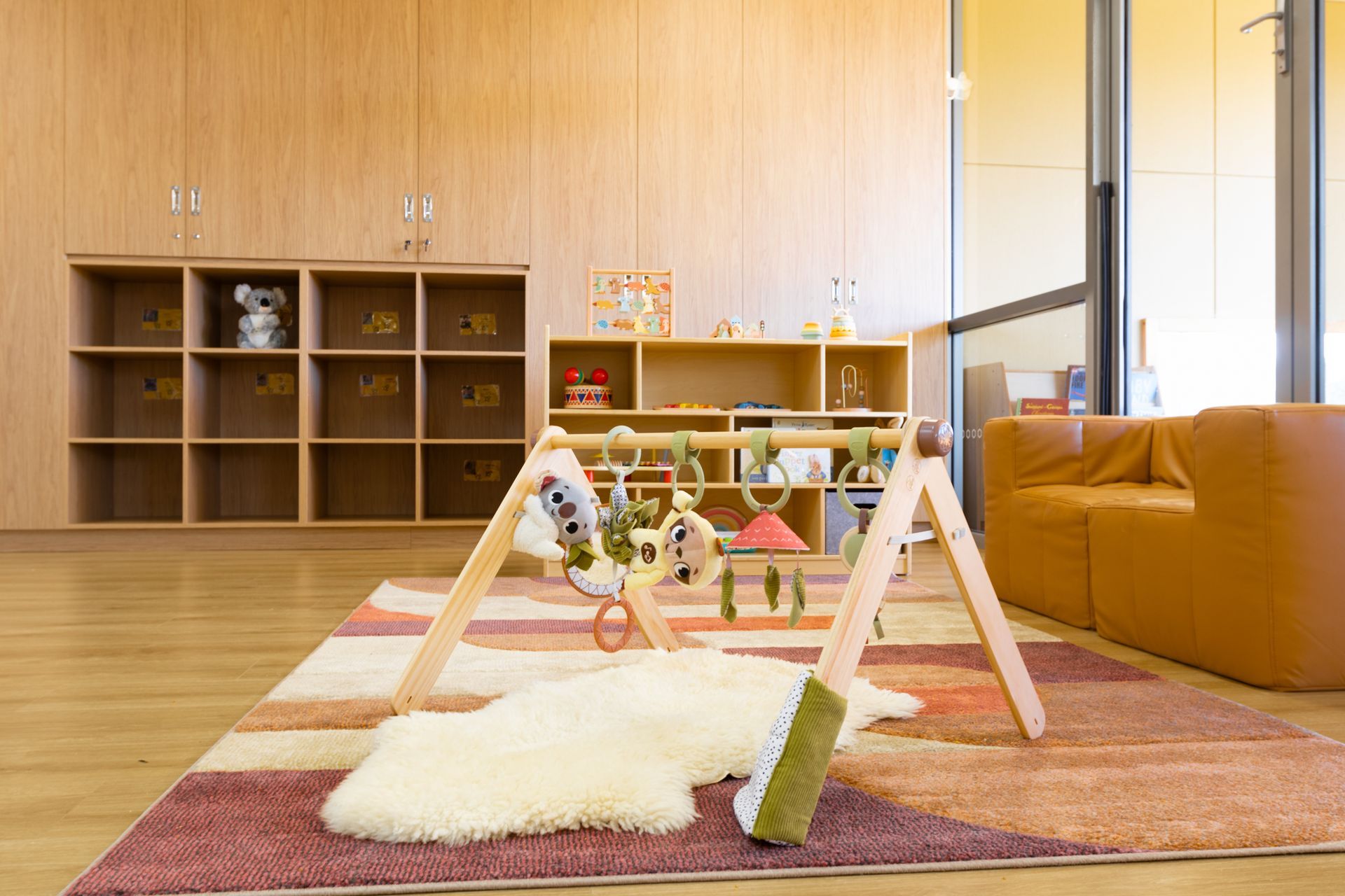 A baby gym is sitting on a rug in a room with a couch.