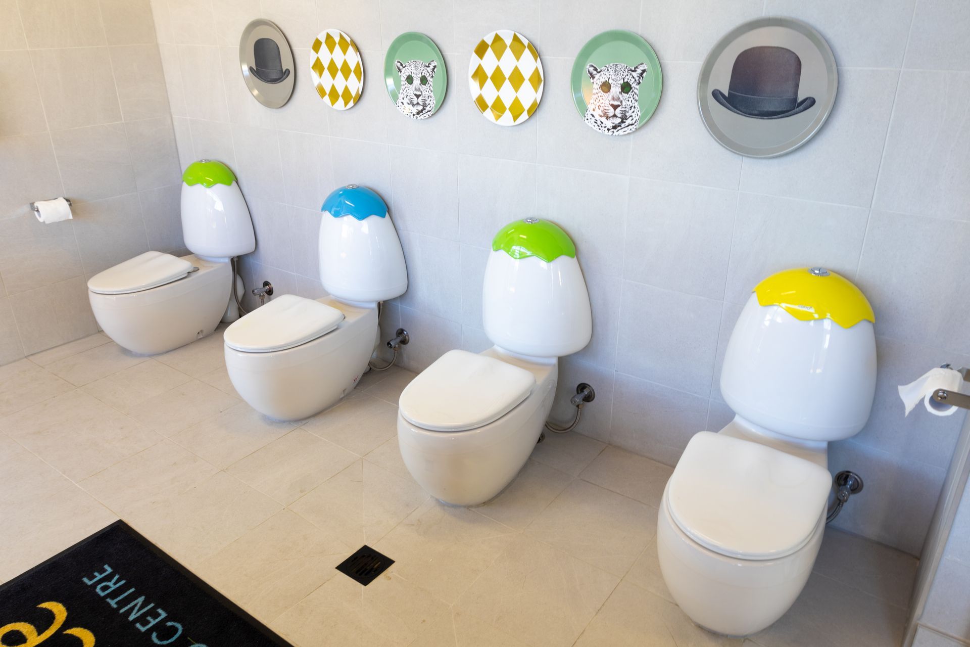 A row of toilets in a bathroom with plates on the wall