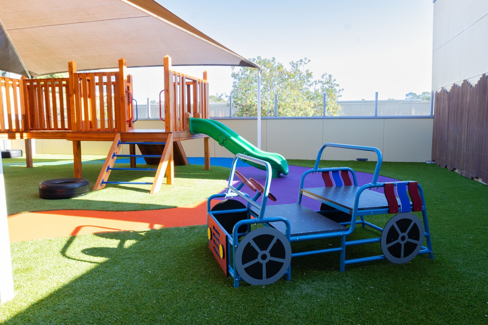 A playground with a slide and a car in the middle of it.