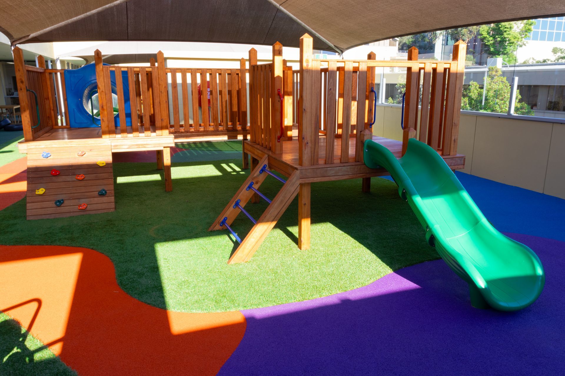 A playground with a green slide and a wooden structure