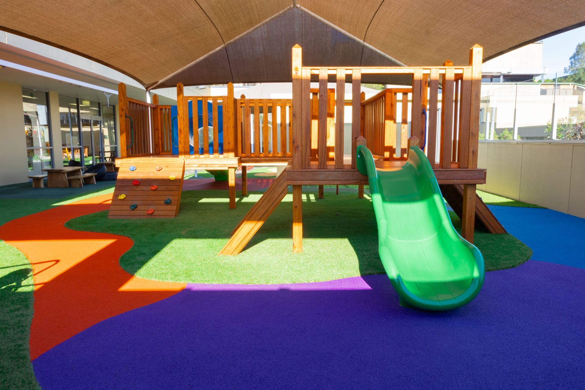A playground with a green slide and a wooden structure