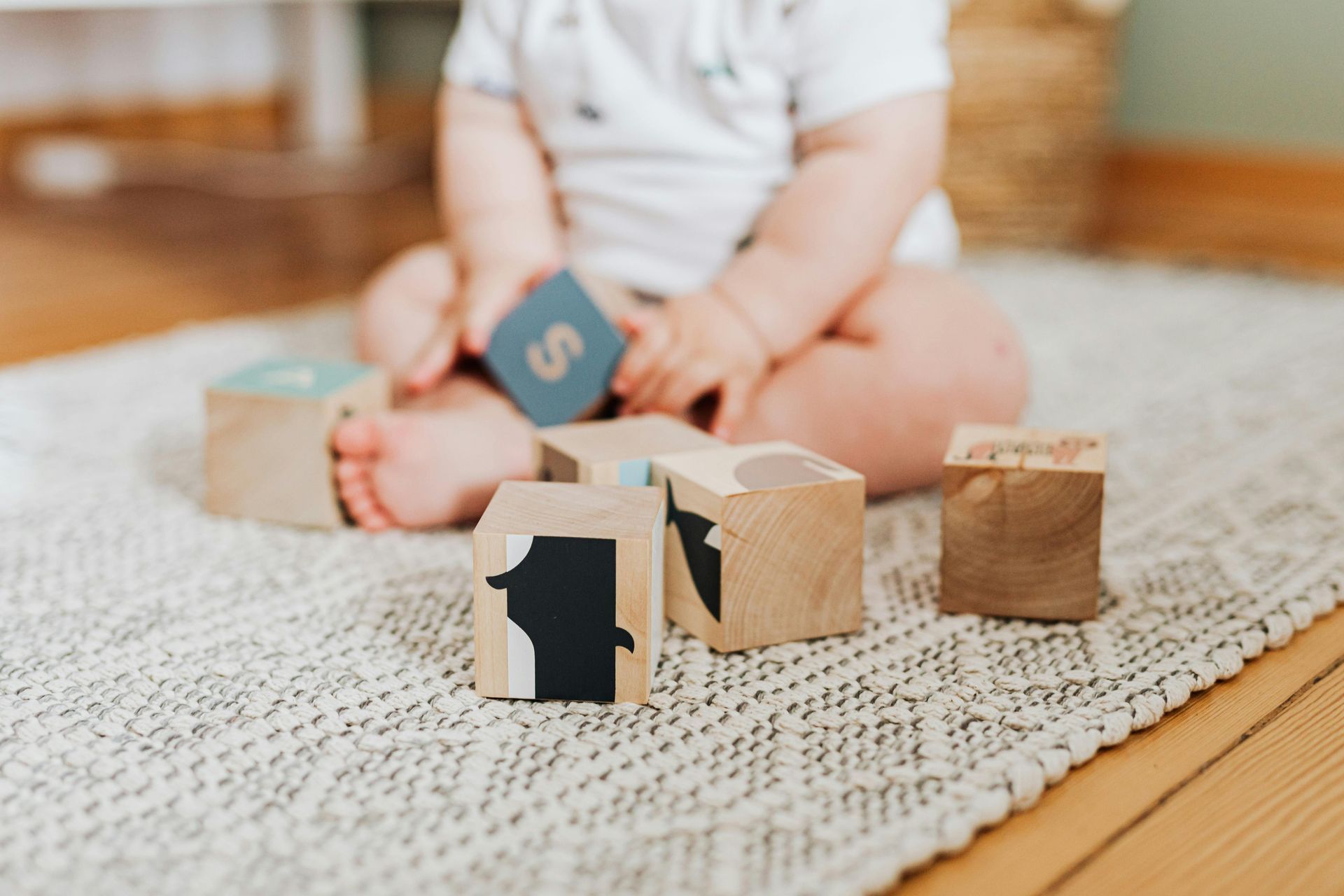 A baby is sitting on the floor playing with wooden blocks.