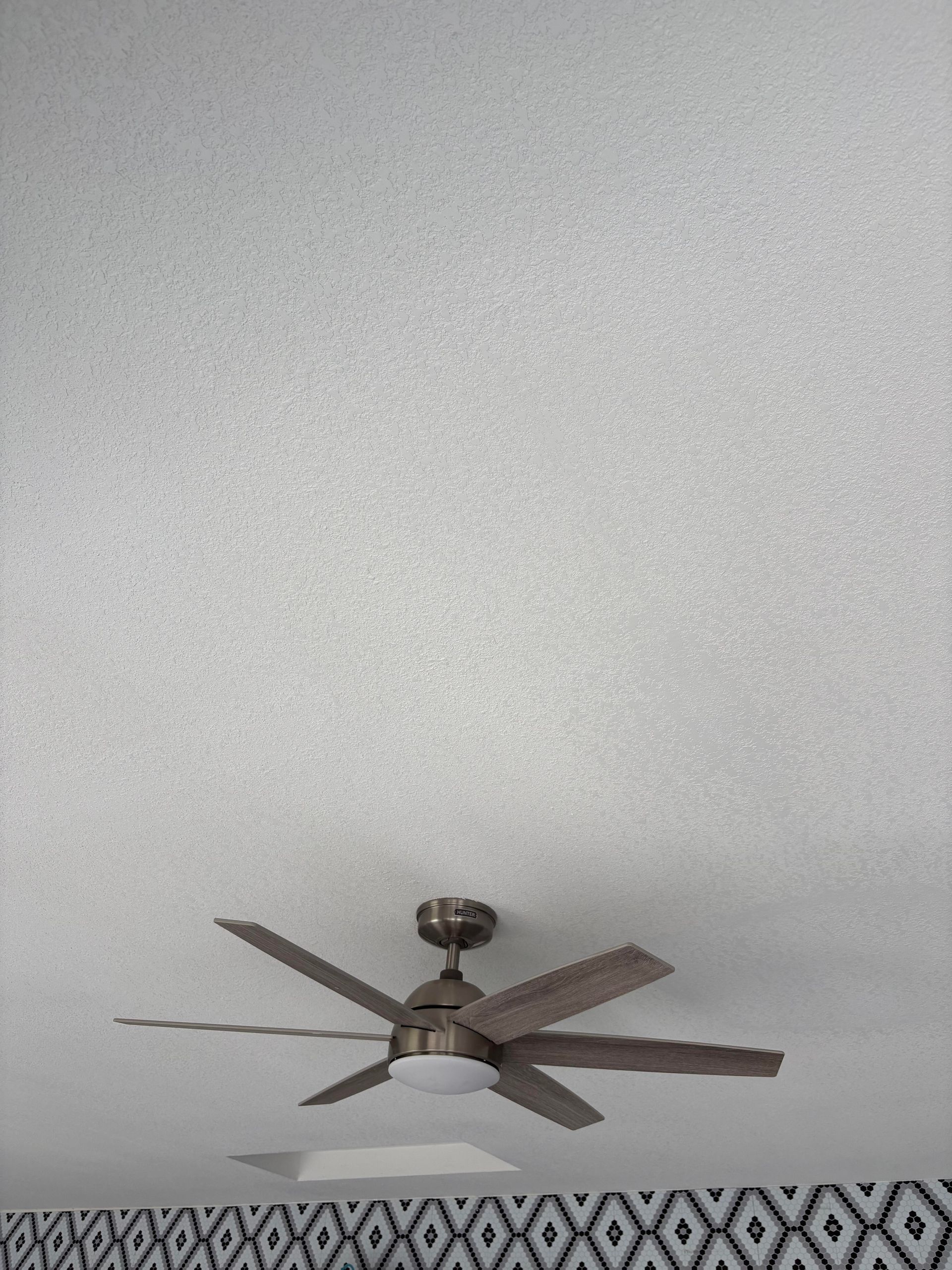 Ceiling fan with light attached, mounted on a textured white ceiling.