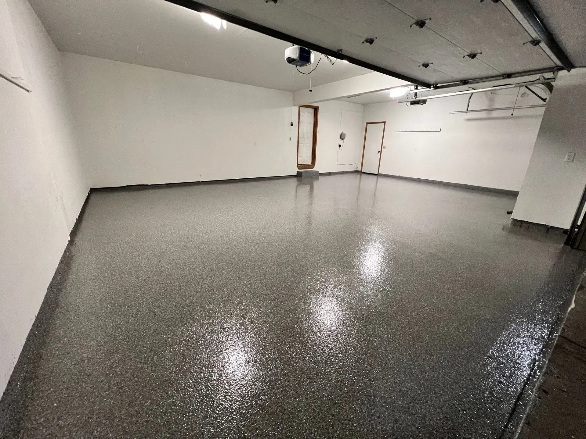 Empty garage with a gray, speckled epoxy floor and white walls.