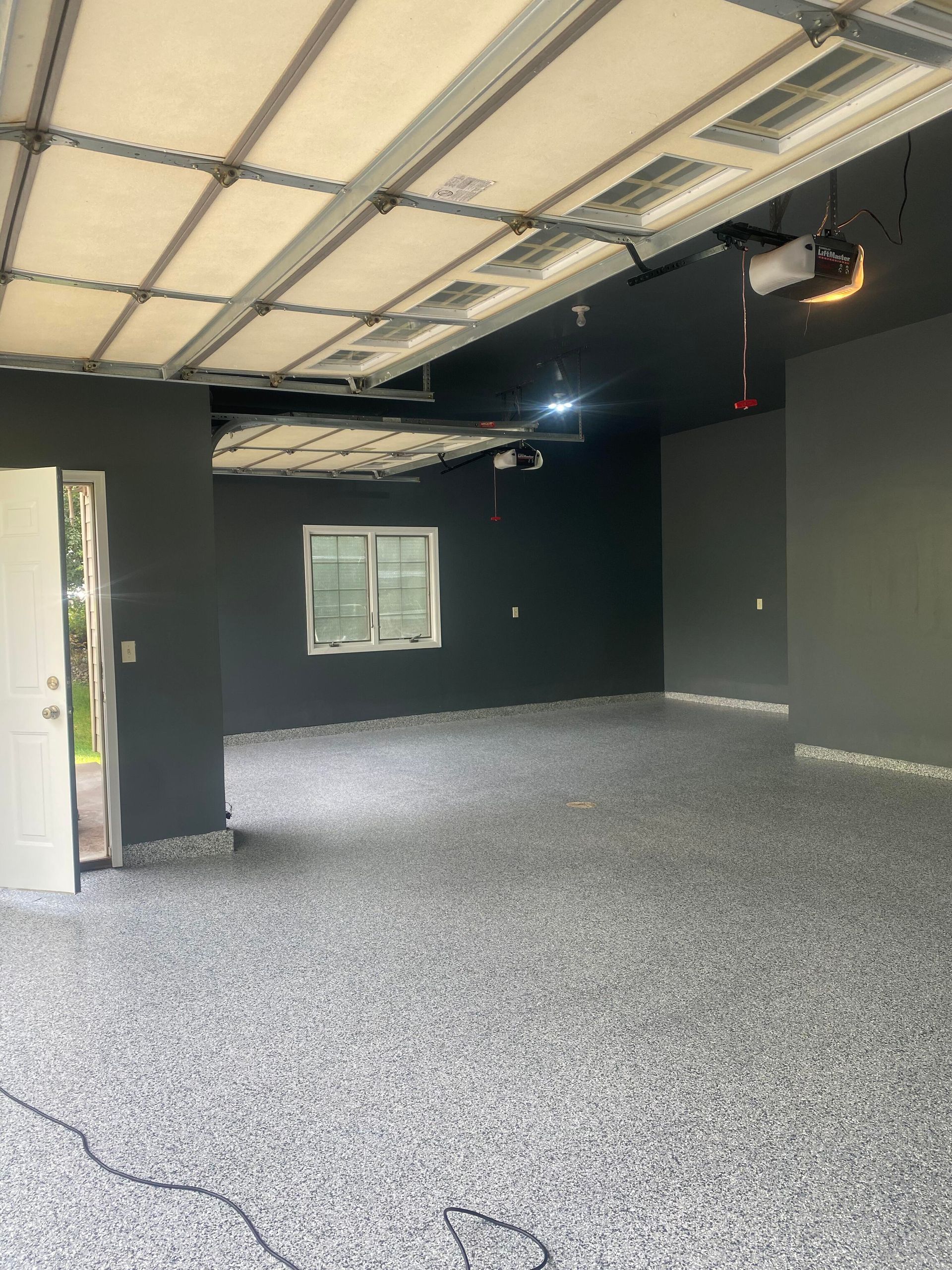 Spacious garage with dark gray walls, gray speckled floor, and a white garage door.