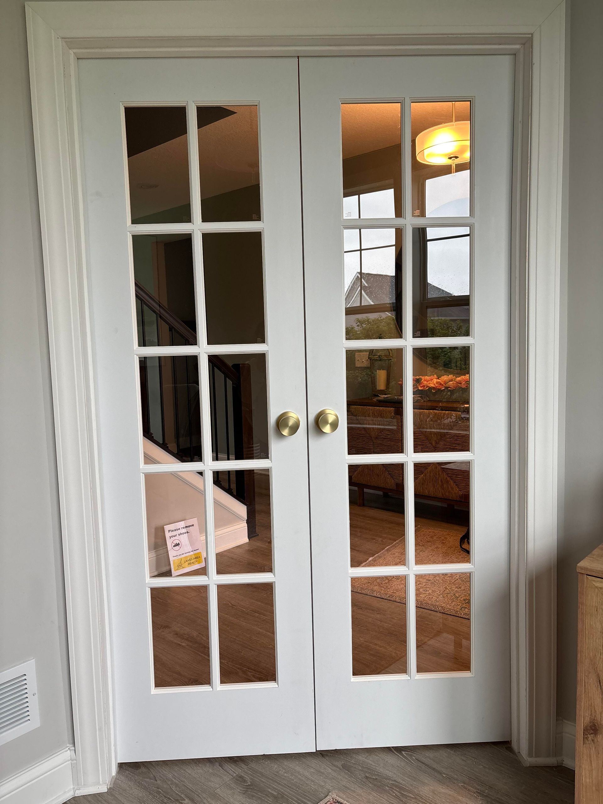 White French doors with multiple glass panes, gold doorknobs, framed by white trim.