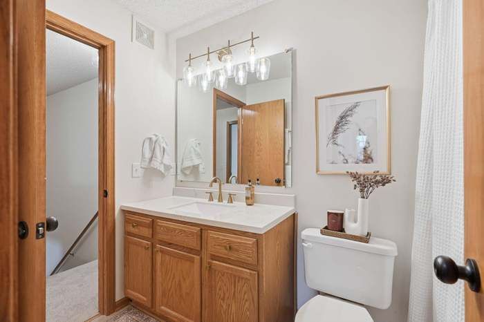 Bathroom with wood vanity, white countertop, and gold accents.