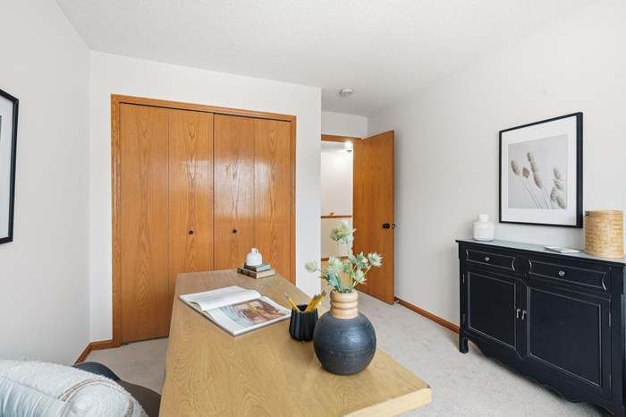A room with a desk, closet, and a cabinet, all in neutral tones.