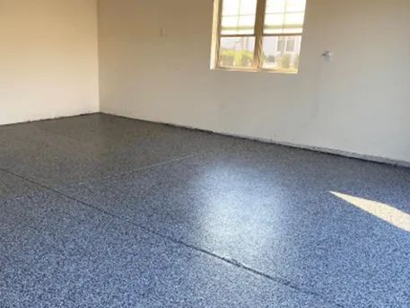 Garage with a blue and gray speckled epoxy floor, white walls, and a window.