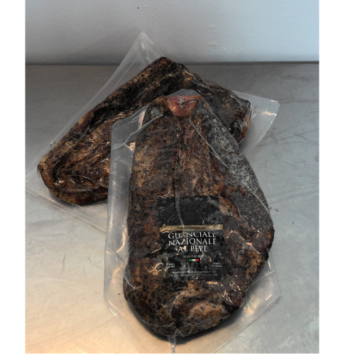 Due confezioni sottovuoto di carne di manzo, di colore marrone scuro, appoggiate su una superficie metallica.