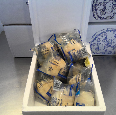 Contenitore termico in polistirolo bianco riempito con alimenti confezionati singolarmente.