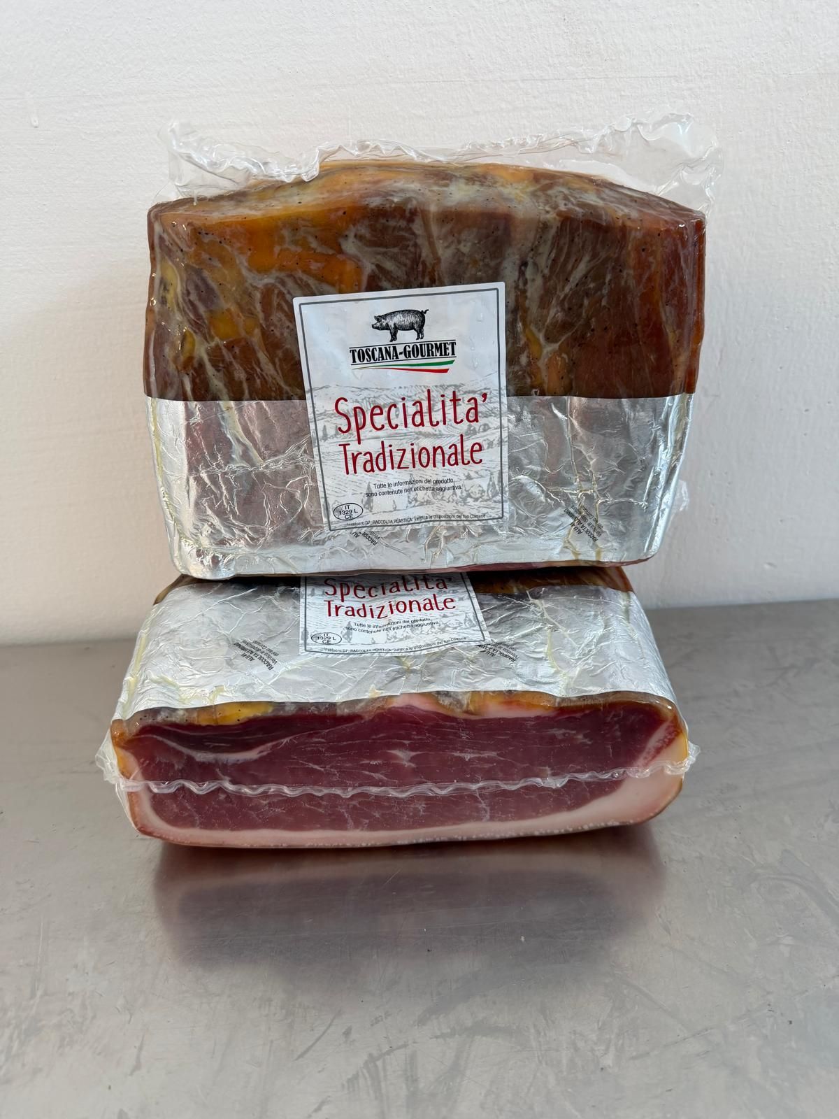 Due confezioni sottovuoto di prosciutto italiano con etichette, impilate una sull'altra.
