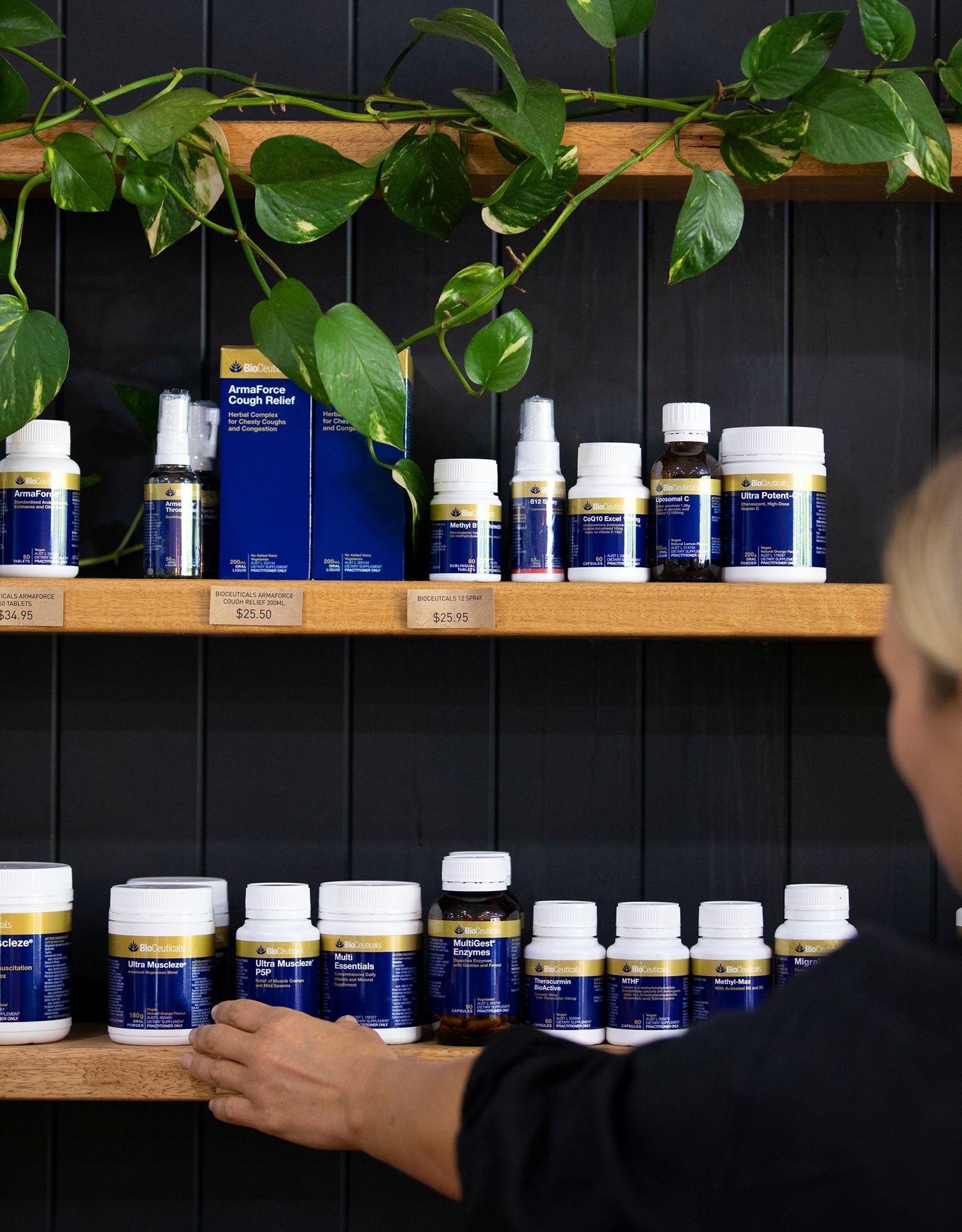 Woman Reaching for a Product on a Shelf Displaying Blue and White Supplements — The Real Grocer In Golden Beach, QLD