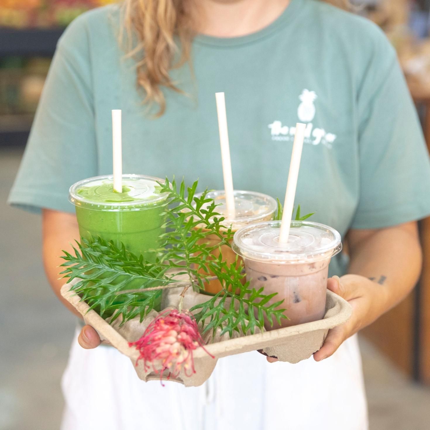 A Woman Is Holding A Tray Of Smoothies With Straws — The Real Grocer In Golden Beach, QLD