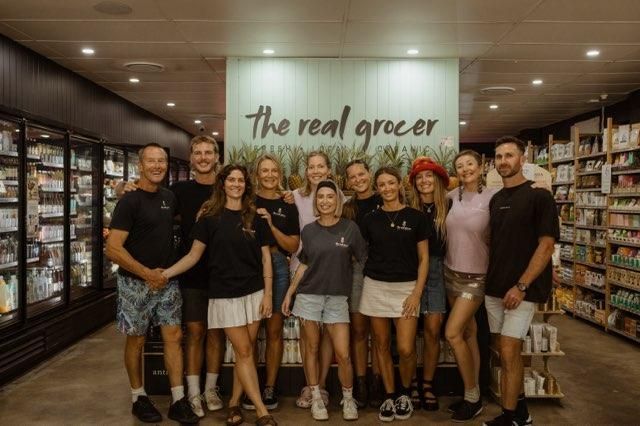 A Group Of People Are Posing For A Picture In A Grocery Store — The Real Grocer In Golden Beach, QLD