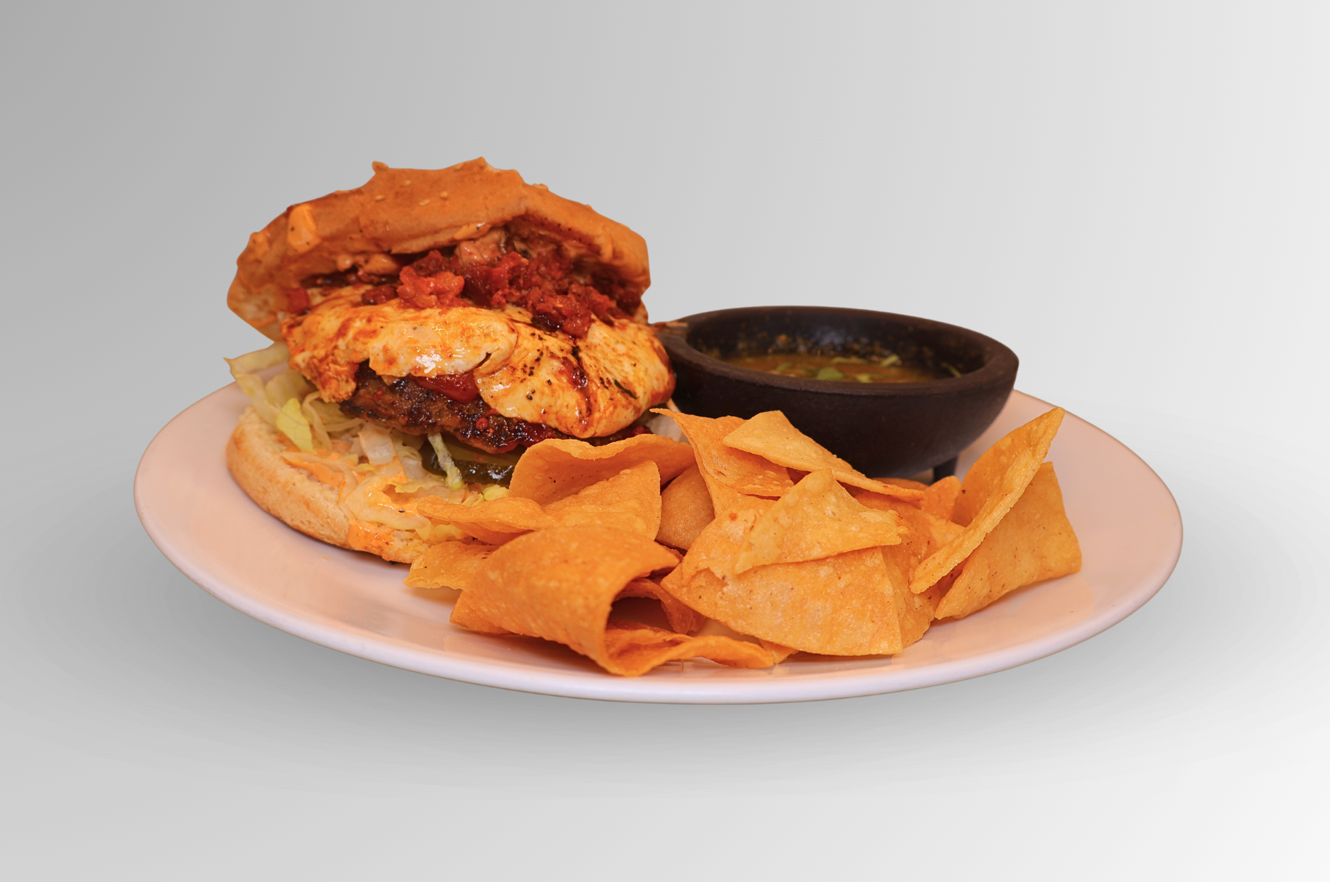 Hamburger with salsa, tortilla chips, on a plate.