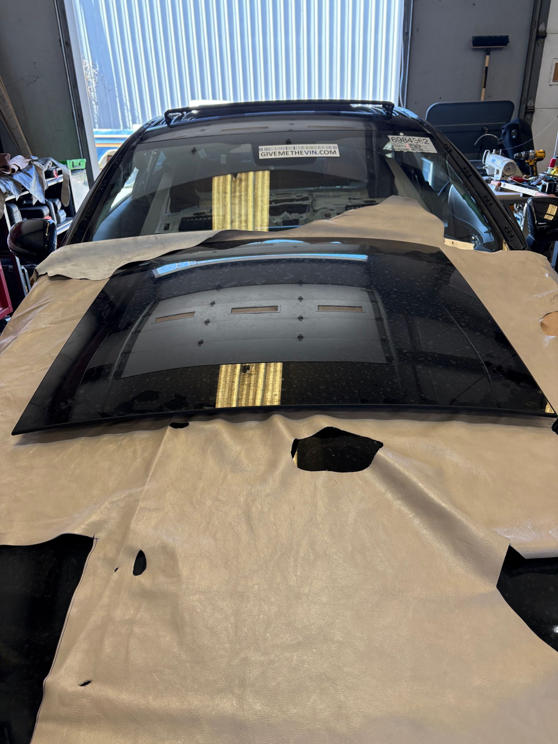 A black car is sitting on top of a piece of paper in a garage.