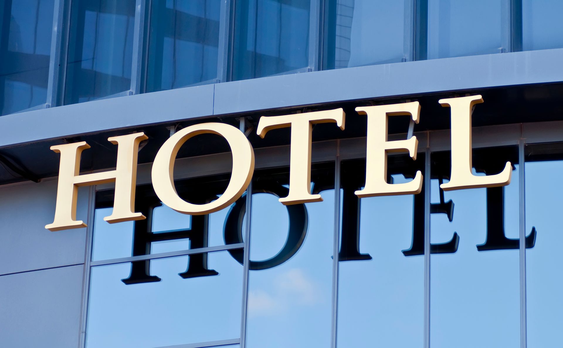 A gold hotel sign mounted on a modern glass building exterior.