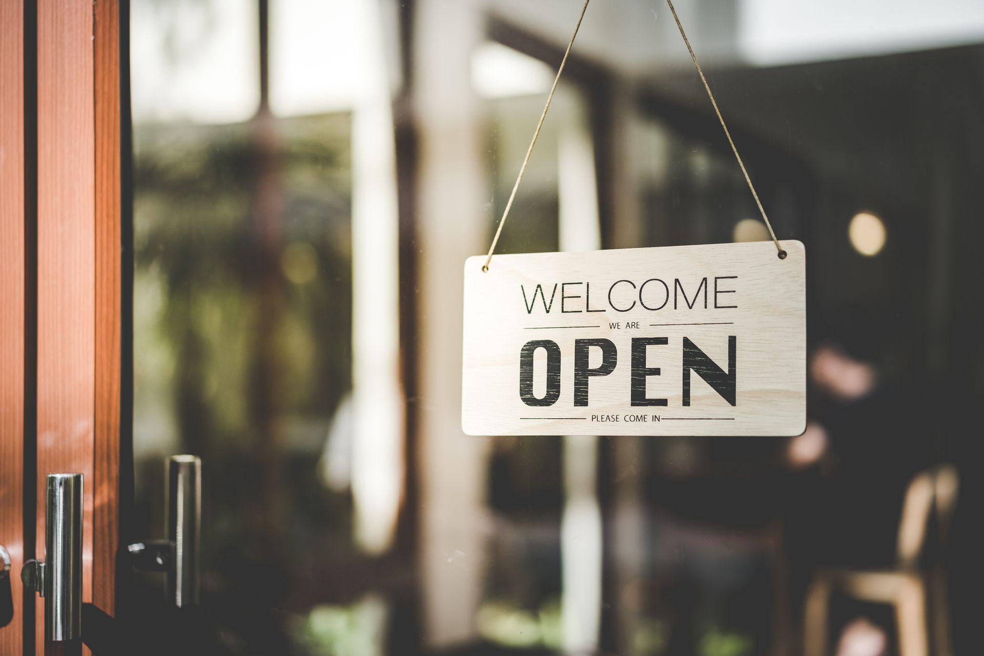 Open sign hanging in coffee shop window with colorful bokeh lights, showcasing interior signage.