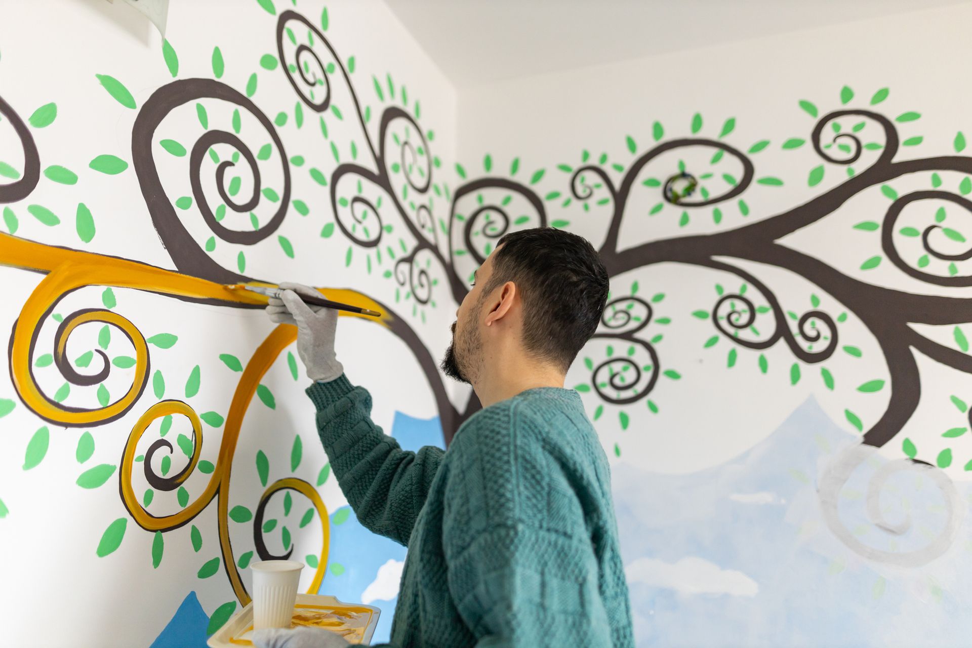 An artist in Michigan paints an interior wall mural with colourful and intricate details, showcasing