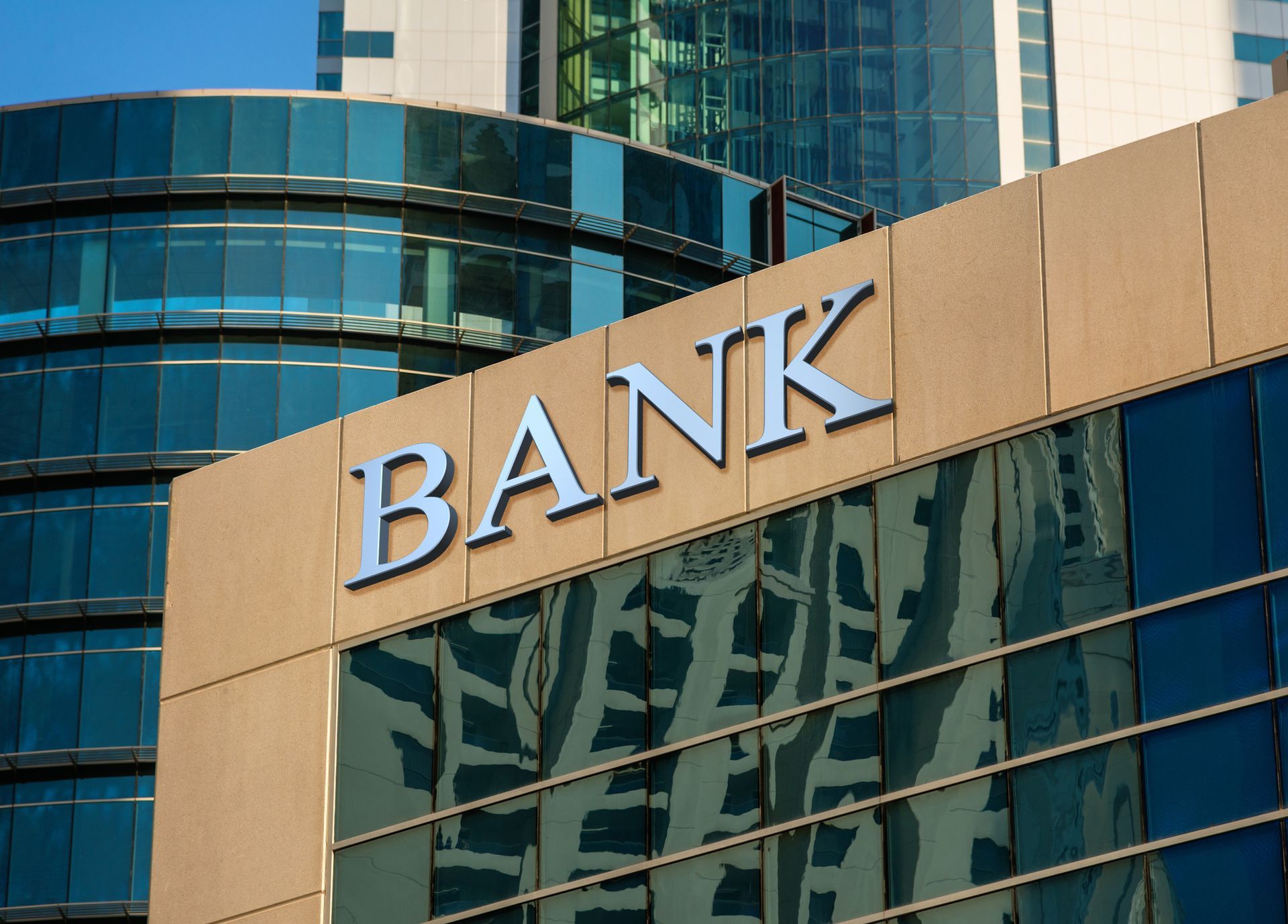 Exterior signage for a bank displayed on the glass wall of a modern business center.