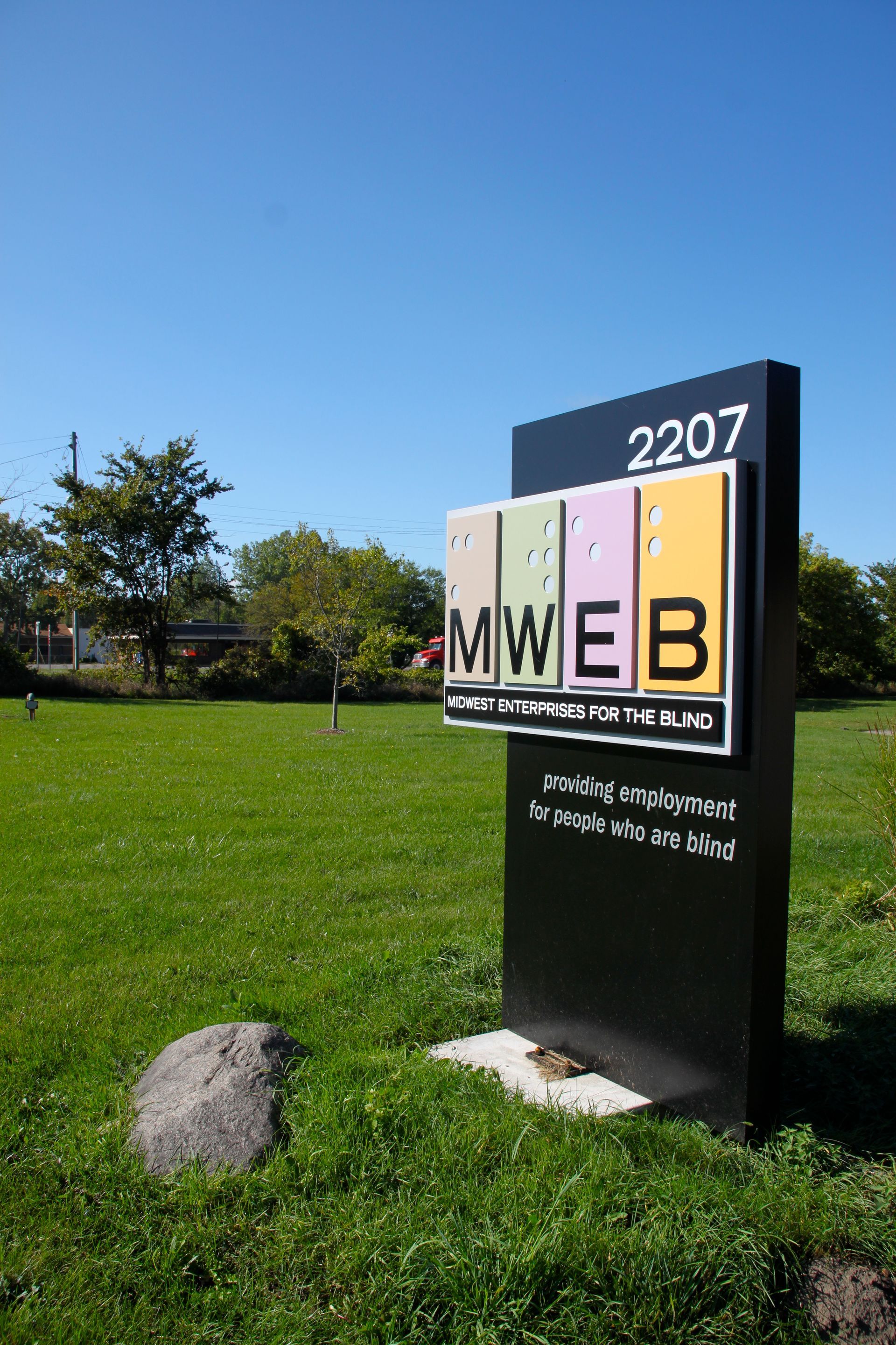 A sign for mweb is sitting in the middle of a grassy field.