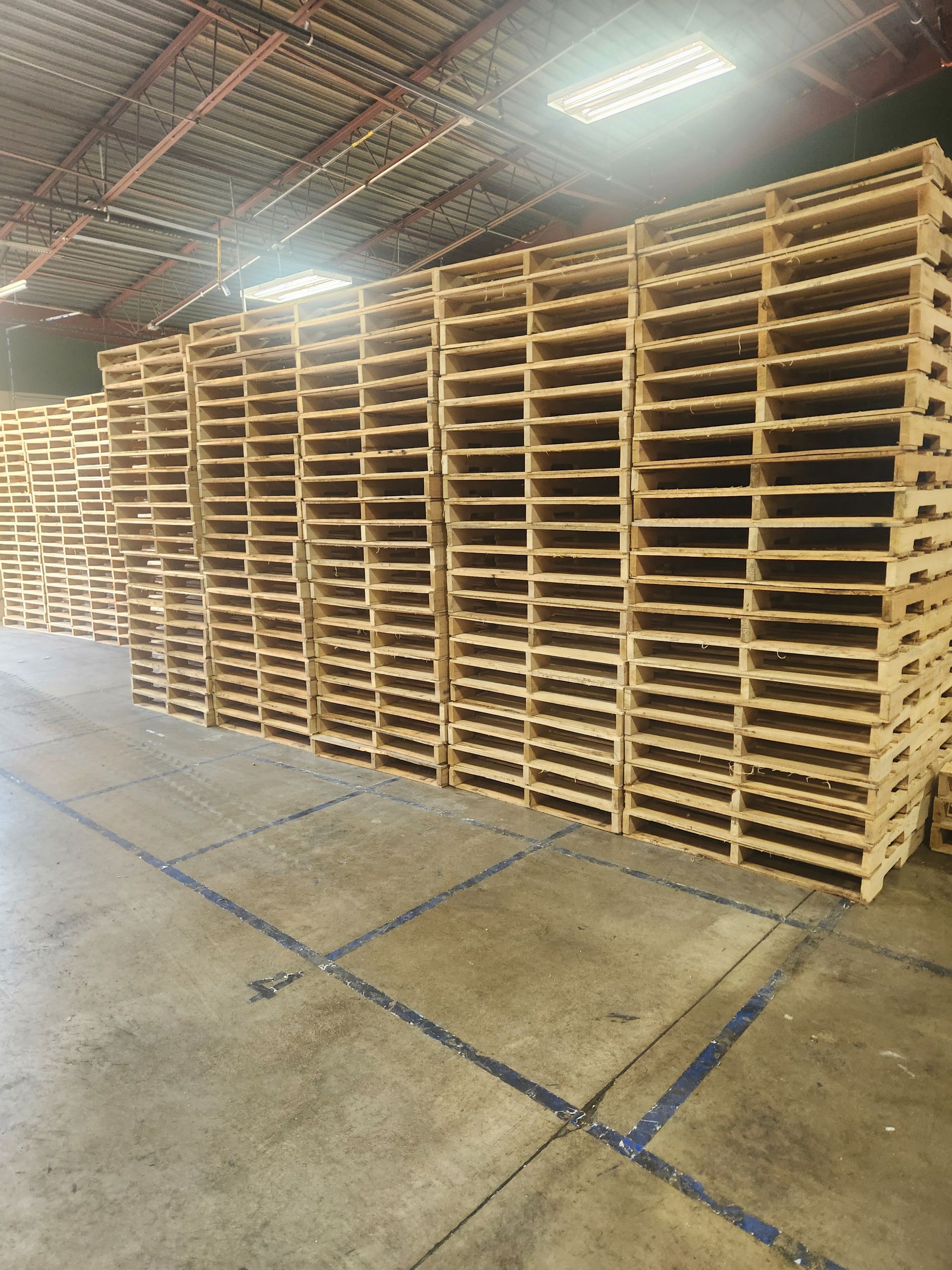 A warehouse filled with lots of wooden pallets stacked on top of each other.