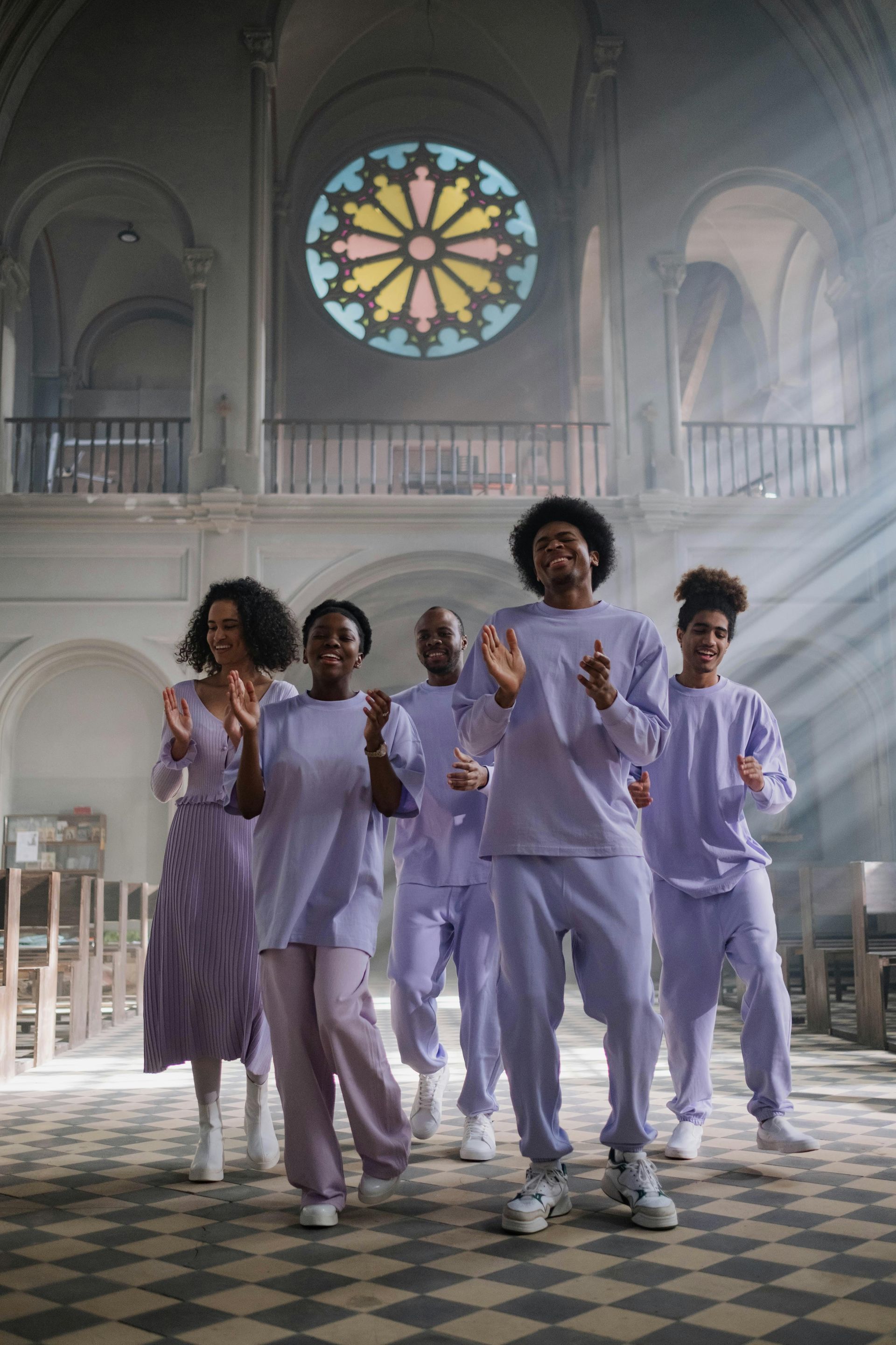 A group of people in purple clothes are dancing in a church.