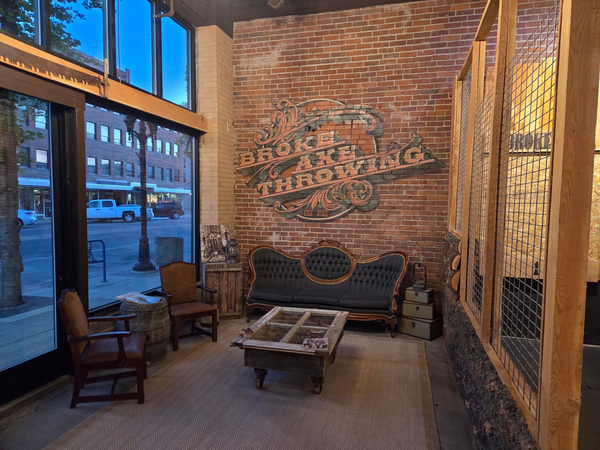 Cozy brick-walled seating area with vintage chairs, a sofa, and a low table by large windows