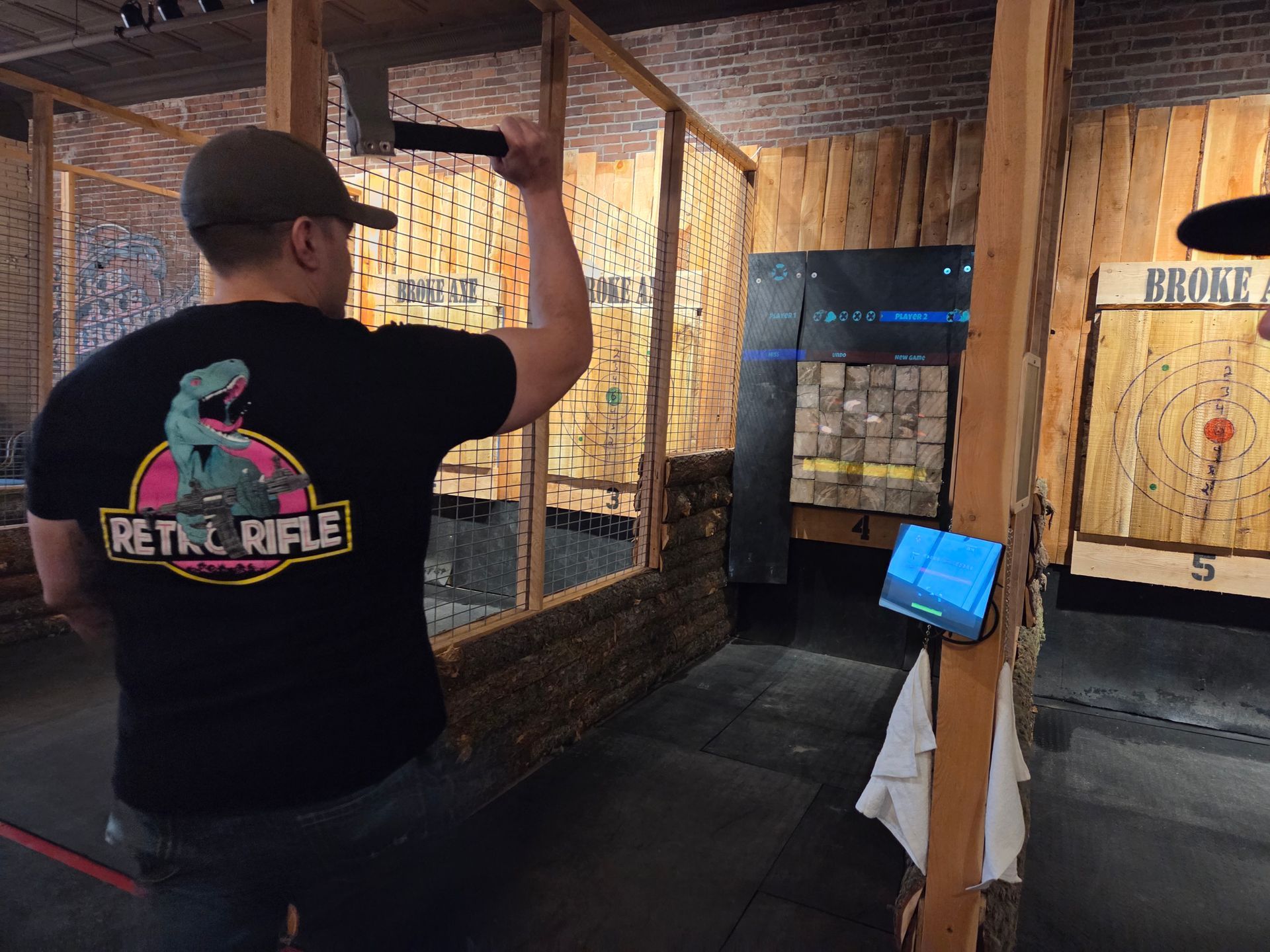 Person aiming a axe in an indoor shooting range lane with brick walls and a target downrange